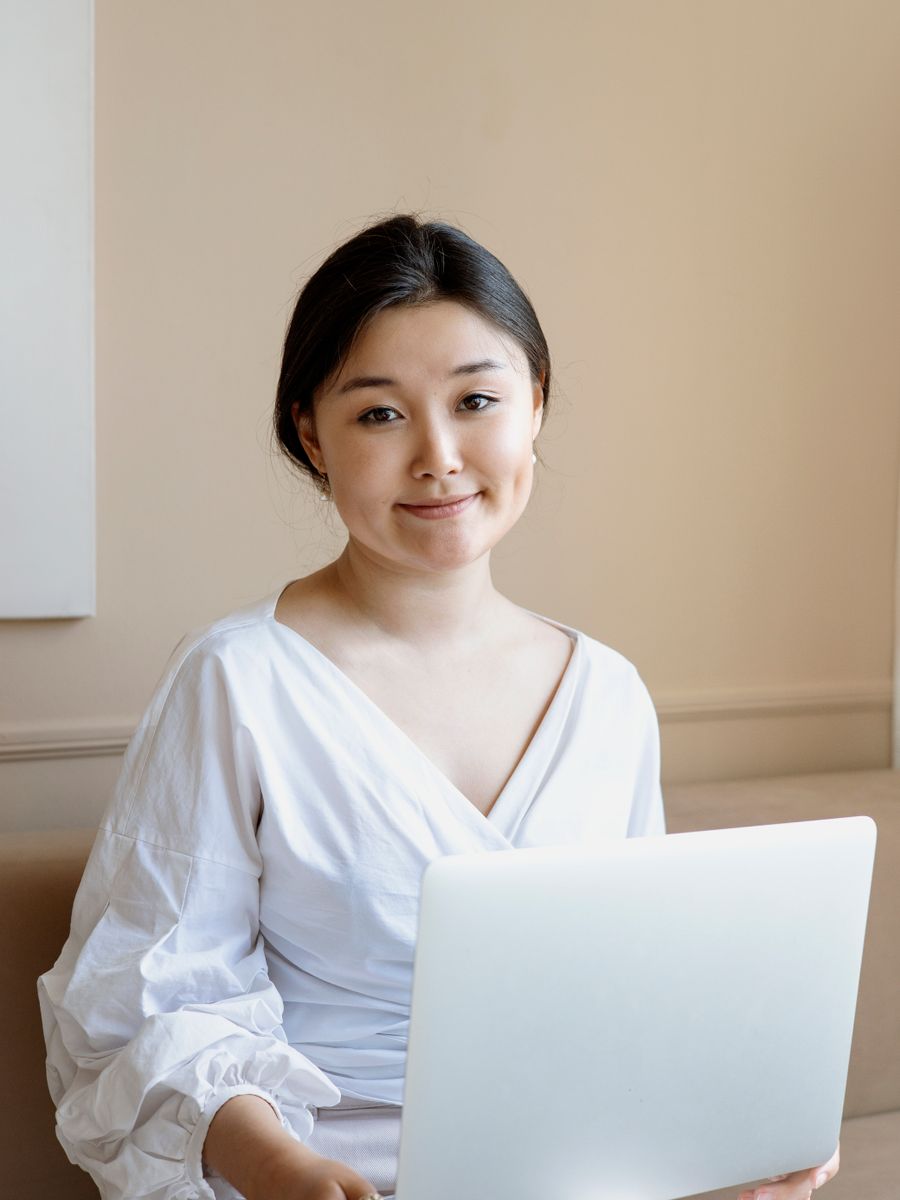 A woman sitting with an open laptop on her lap.
