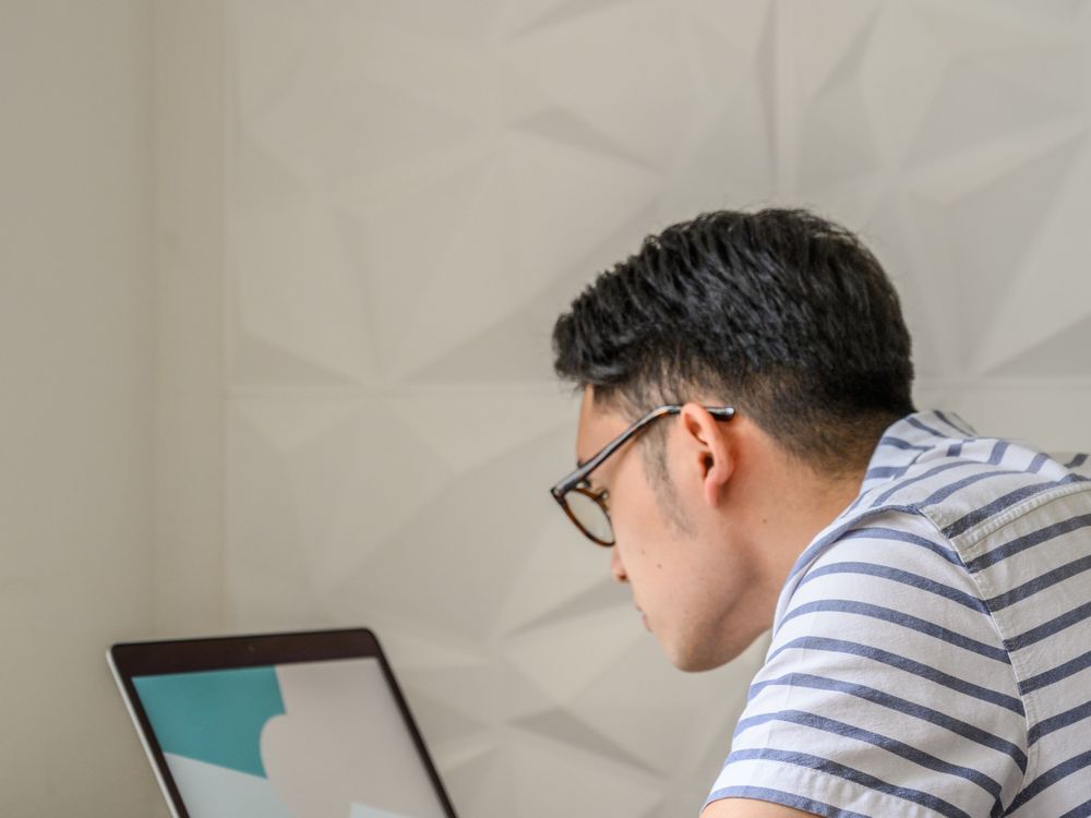 A man working at a laptop at a small round table.
